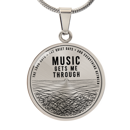 Silver circle pendant necklace featuring “Music Gets Me Through” with abstract flowing line artwork and the words “The Loud Days, The Quiet Days and Everything Between”